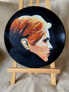 Seitliches Portrait von Bowie in Orangetönen (Album Low) auf einer Schallplatte